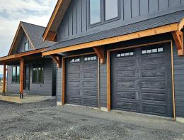 Two carbon oak woodtone raised panel garage doors with arched window lites on a craftsman-style home
