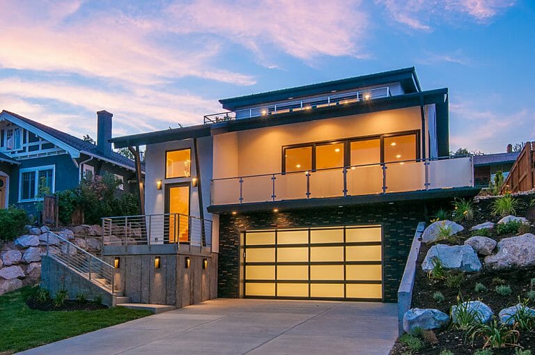 A home lit up at dusk with a glass garage door installed.